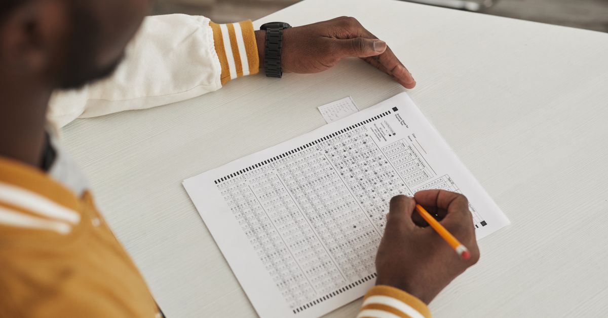 Focused student marking answers on a multiple choice exam sheet in a classroom setting.